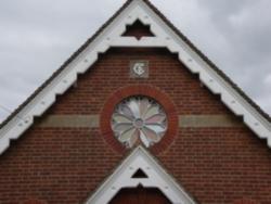 Front apex of building showing monogram, inscription & circular window